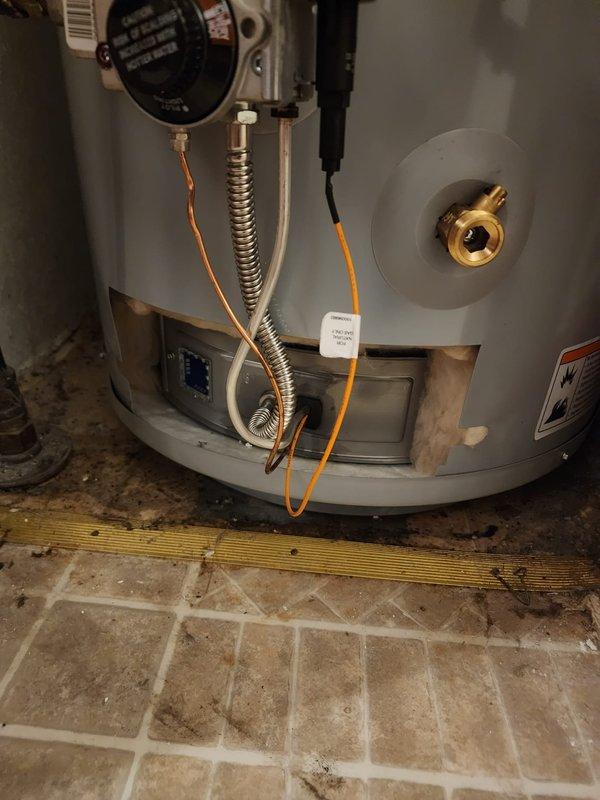 Completed installation of a 40-gallon State ProLine tanked water heater in a mobile home utility closet. Positioned unit on yellow plastic drain pan over herringbone-patterned tile flooring and secured to wall with metal strapping for seismic safety. Connected water supply lines with blue shut-off valves, installed pressure relief valve with discharge piping, and completed electrical connections using flexible conduit. Verified all plumbing connections for leaks, tested unit operation, and confirmed proper venting through existing exhaust system.