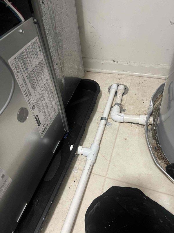 Responded to water leak service call and discovered moisture accumulation in the condensate drip pan of HVAC unit 5-9. Inspected the condensate drainage system, including PVC drain lines and connections, and documented the condition with photos showing water present in the drain pan beneath the air handler. Verified proper drain line configuration and cleared any potential blockages to restore normal condensate flow and prevent future water accumulation in the mechanical room.
