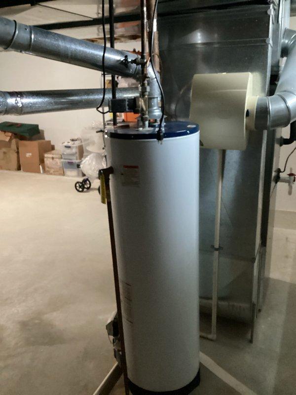 Conducted on-site evaluation of existing residential water heater installation in basement utility room. Assessed current white cylindrical water heater unit with standard venting configuration, including metal ductwork connections and copper supply piping. Documented equipment specifications, clearances, and existing plumbing connections to prepare comprehensive replacement estimate for 10-12 year old unit approaching end of service life.