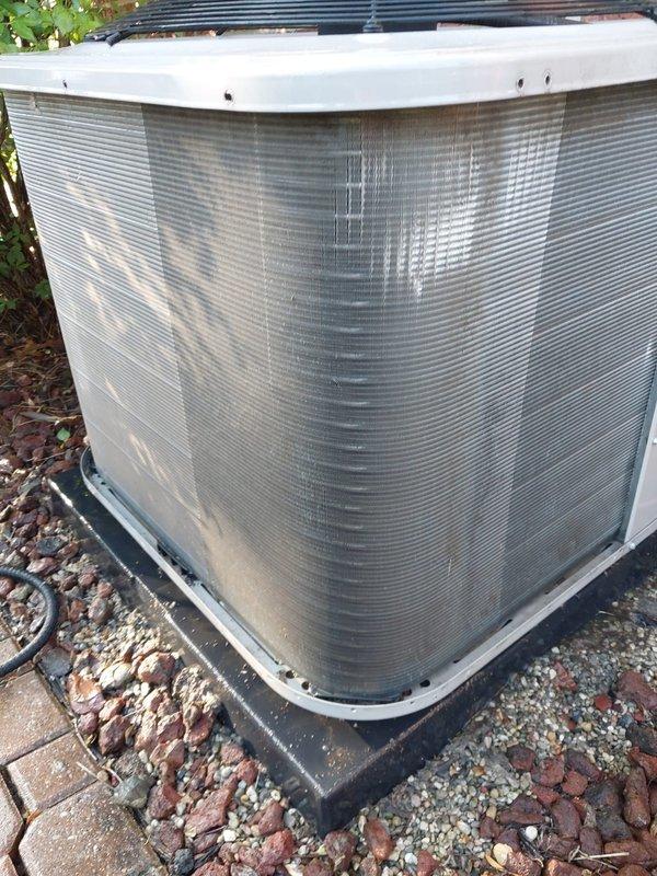 Responded to service call for noisy AC fan. Upon inspection of outdoor condensing unit, found system operational with compressor, condenser coil, and fan assembly in functional condition. Verified unit was running within normal parameters and documented equipment condition with photos showing standard residential HVAC installation with protective mesh screening and proper mounting on concrete pad with gravel base.