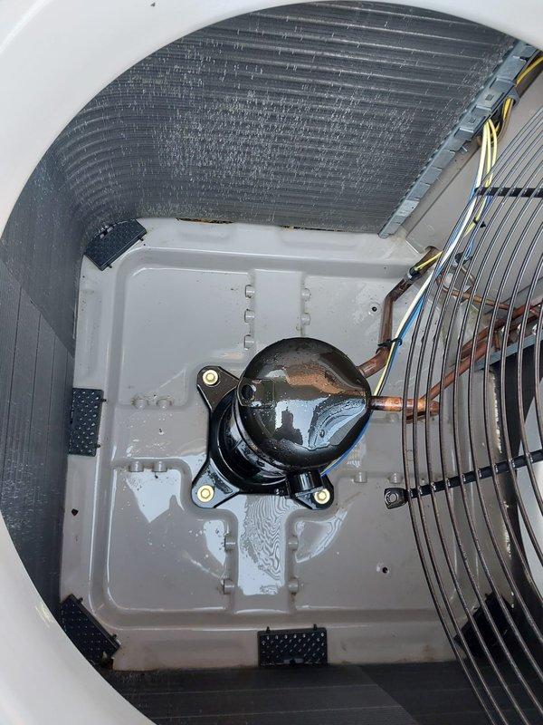 Responded to service call for noisy AC fan. Upon inspection of outdoor condensing unit, found system operational with compressor, condenser coil, and fan assembly in functional condition. Verified unit was running within normal parameters and documented equipment condition with photos showing standard residential HVAC installation with protective mesh screening and proper mounting on concrete pad with gravel base.