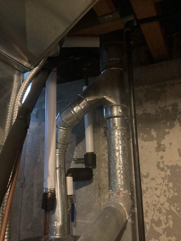 Conducted on-site assessment of non-functional HVAC system experiencing loss of cooling capacity. System was blowing air but not producing cold air, indicating potential compressor failure, refrigerant loss, or air handler malfunction. Evaluated existing furnace and air conditioning equipment installed in basement utility area, including vertical air handler configuration with stacked components, metallic vent piping with 90-degree elbow joints, flexible aluminum ductwork, and PVC condensate drainage lines. Documented current system condition through photographic evidence showing aging installation with exposed insulation and mechanical components mounted within confined space. Provided comprehensive estimate for full system replacement of both furnace and air conditioning units, while also discussing potential repair options with homeowner as requested.