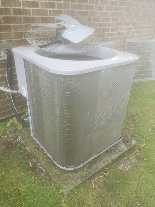 Completed comprehensive AC tune-up on outdoor condenser unit located on side of residential property. Performed full system inspection including electrical connections, refrigerant lines, compressor operation, and capacitor functionality. Observed frost and ice buildup in drain pan area during internal inspection, indicating normal condensation during cooling cycle. Verified compressor mounting on vibration dampeners, checked all copper refrigerant line connections for integrity, and confirmed proper fan operation and grille protection. System operating within normal parameters with no immediate service concerns identified.