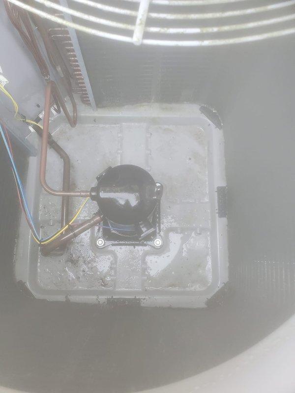 Completed comprehensive AC tune-up on outdoor condenser unit located on side of residential property. Performed full system inspection including electrical connections, refrigerant lines, compressor operation, and capacitor functionality. Observed frost and ice buildup in drain pan area during internal inspection, indicating normal condensation during cooling cycle. Verified compressor mounting on vibration dampeners, checked all copper refrigerant line connections for integrity, and confirmed proper fan operation and grille protection. System operating within normal parameters with no immediate service concerns identified.