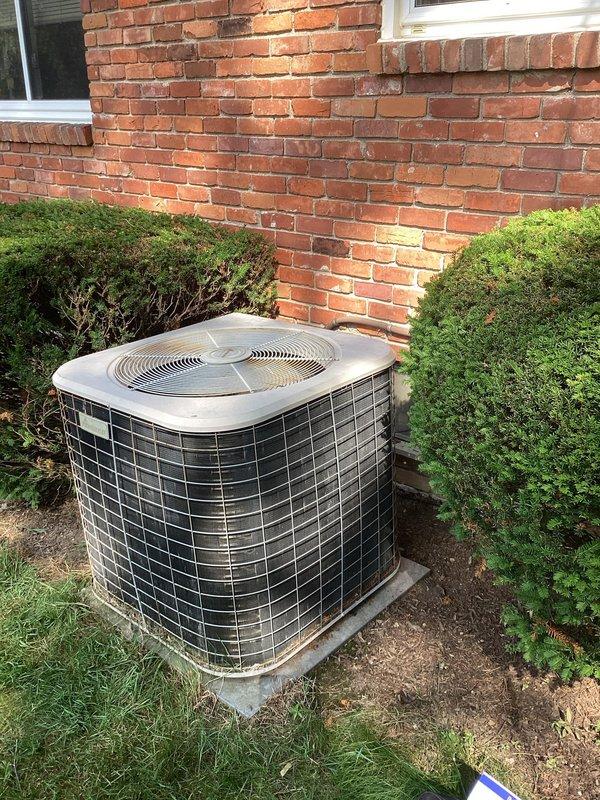 Performed comprehensive evaluation of existing R-22 air conditioning system found to be 5-6 pounds low on refrigerant. Due to the age of the unit, obsolete R-22 refrigerant requirements, and potential underlying leak issues, recommended complete system replacement. Documented current outdoor condenser unit condition with detailed photographs showing equipment positioning against brick exterior, copper refrigerant line routing, and overall installation setup for replacement planning and customer review.