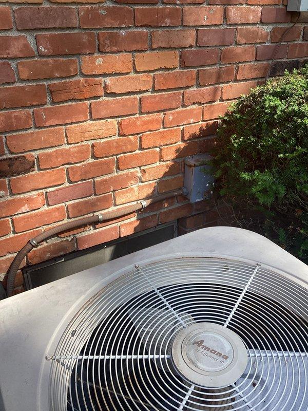 Performed comprehensive evaluation of existing R-22 air conditioning system found to be 5-6 pounds low on refrigerant. Due to the age of the unit, obsolete R-22 refrigerant requirements, and potential underlying leak issues, recommended complete system replacement. Documented current outdoor condenser unit condition with detailed photographs showing equipment positioning against brick exterior, copper refrigerant line routing, and overall installation setup for replacement planning and customer review.