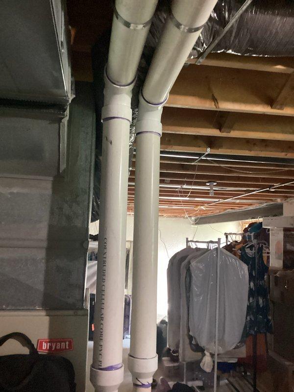 Completed HVAC system assessment for replacement estimate on residential property with aging equipment. Air conditioning unit at 27 years old and furnace at 13 years old were evaluated following a circuit board failure caused by power outage. System was restored to operational cooling status. Documented existing gray furnace unit in basement with metal ductwork configuration and vertical plumbing infrastructure. Photographed current equipment condition and mechanical room layout to support replacement recommendation due to advanced age of cooling system and moderate age of heating equipment.