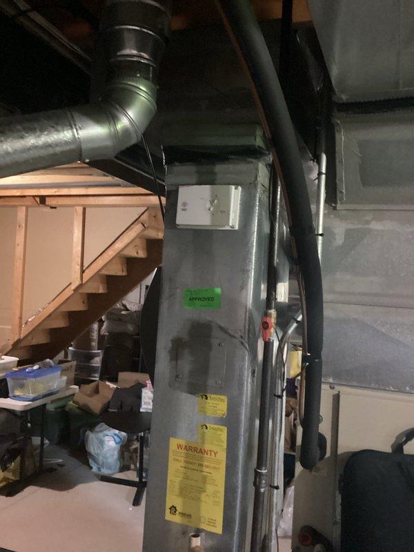 Completed HVAC system assessment for replacement estimate on residential property with aging equipment. Air conditioning unit at 27 years old and furnace at 13 years old were evaluated following a circuit board failure caused by power outage. System was restored to operational cooling status. Documented existing gray furnace unit in basement with metal ductwork configuration and vertical plumbing infrastructure. Photographed current equipment condition and mechanical room layout to support replacement recommendation due to advanced age of cooling system and moderate age of heating equipment.