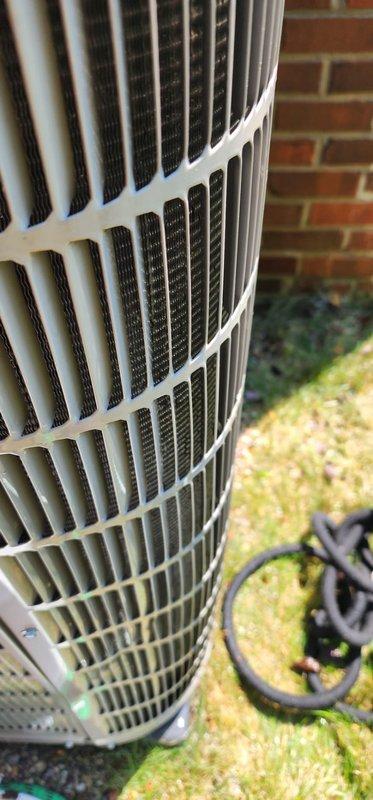 Completed comprehensive AC maintenance inspection on outdoor condensing unit. Examined condenser coil assembly, confirming fins are clean and free of debris with adequate airflow through protective grille. Documented standing water accumulation in condensate drain pan with visible sediment and discoloration, indicating potential drainage restriction requiring attention during future service visit.