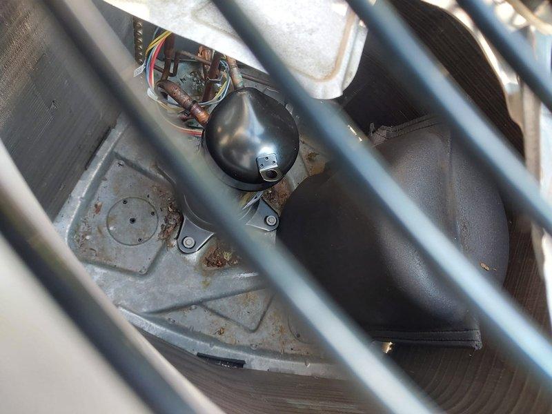 Responded to customer complaint of unusual noises and reduced cooling performance. Upon inspection, found outdoor condensing unit with visible rust staining on cabinet panels and debris accumulation around compressor mounting area. Examined compressor, electrical connections, and condenser coil through protective grille. All electrical terminals showed proper connections with no signs of arcing or damage. Compressor appeared mechanically sound with secure mounting. Advised customer of equipment condition and recommended routine maintenance to address minor corrosion and debris buildup to ensure optimal system performance.