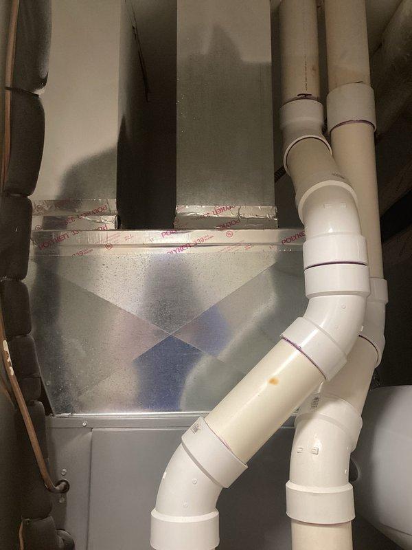 Responded to service call for non-operational air conditioning system and outdoor condenser unit. Evaluated existing nine-year-old four-ton HVAC system with condenser located outside near garage and air handler positioned upstairs. Conducted comprehensive assessment of both indoor and outdoor equipment to determine failure points and system viability. Documented current installation including ComfortMaker air handler unit, associated ductwork, PVC condensate drainage lines, and ventilation components. Photographed existing equipment configuration showing metallic air handler with proper condensate piping, white PVC exhaust/intake venting, and standard residential HVAC installation setup. Provided detailed replacement estimate for complete four-ton system upgrade to address equipment failure and restore cooling functionality to residence.