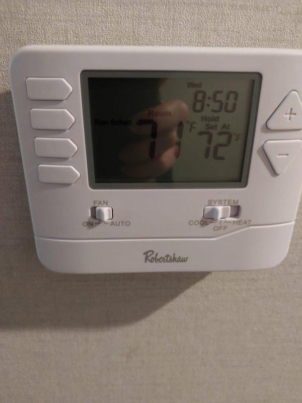 Responded to no cooling complaint on 2024 model Robertshaw thermostat system with NADA036GDCC air handler unit. Upon arrival, verified thermostat display showing 72°F room temperature with system controls accessible. Documented thermostat settings with fan switch in AUTO position and system switch available for COOL/OFF/HEAT operation. Inspected air handler unit and recorded equipment specifications including serial number J240659216, confirming R-410A refrigerant system with proper labeling and documentation present.