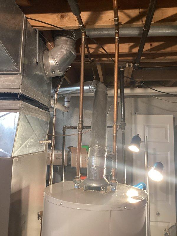 Completed on-site assessment for water heater replacement in basement utility area. Evaluated existing white cylindrical water heater, associated copper supply and distribution piping, venting requirements, and clearances relative to HVAC ductwork and electrical systems. Documented current installation configuration including vertical copper pipe routing, ceiling-mounted support systems, and proximity to mechanical equipment. Provided estimate for replacement unit installation scheduled for May 7th, with availability for earlier completion if required.