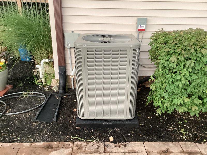 Completed full HVAC system installation including new Lennox furnace and air conditioning unit. The outdoor condenser was positioned on a rubber isolation pad against the exterior wall with proper clearance for airflow and service access, refrigerant lines were run through corrugated protective conduit, and all electrical connections were terminated per manufacturer specifications. Interior installation included the air handler unit with associated condensate management system featuring pump and PVC drainage lines, proper ductwork connections, and all required safety controls and electrical disconnects.