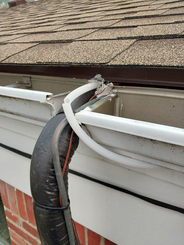 Responded to service call for cracked and leaking condensate drain line. Upon inspection, identified damaged 8-12 inch section of drain piping on exterior of building beneath roofline. Documented existing conditions showing deteriorated black flexible drain hose and associated white PVC drainage components mounted along siding near gutter system. Photographed Lennox furnace unit in mechanical room to verify condensate source and drainage configuration. Completed warranty repair of compromised drain line section to restore proper condensate drainage and eliminate water leakage.