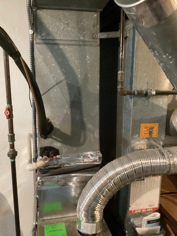 Performed comprehensive assessment of residential air conditioning system found to be low on R-22 refrigerant. The outdoor condensing unit showed significant age-related deterioration with visible weathering, dirt accumulation, and staining on the cabinet surfaces. Given the system's use of R-22 refrigerant, which is being phased out and has become increasingly expensive, combined with the unit's apparent age and condition, recommended full system replacement rather than repair. Documented existing outdoor unit installation against home exterior and indoor furnace/air handler configuration in basement mechanical room for replacement planning purposes.