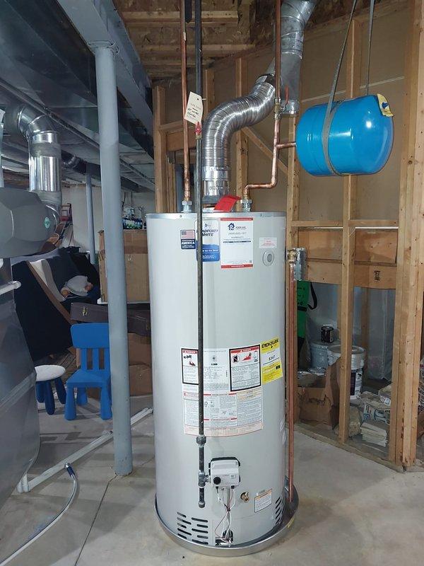Completed installation of 75-gallon residential tanked water heater in basement utility room. Positioned unit on concrete floor, connected water supply lines using copper piping, installed metallic exhaust vent with flexible aluminum ductwork routed to existing ventilation system, and mounted blue expansion tank to ceiling joists with metal strapping. All connections were secured per manufacturer specifications and local plumbing codes, with system tested for proper operation and leak-free performance upon completion.