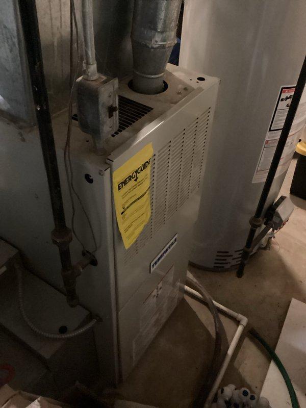 Conducted comprehensive on-site assessment of existing HVAC system for full replacement estimate. Evaluated current furnace and air conditioning equipment, both operational at time of inspection. Documented existing EnergyGuard furnace unit and associated ductwork configuration in basement installation. Photographed equipment conditions showing age-related wear and dust accumulation on metal casing and components. Assessed system layout including duct connections, gas supply infrastructure, and ventilation pathways. Customer inquiry regarding mini-split installation for two rooms over garage without existing ductwork was noted for comfort advisor review, though mini-split systems currently fall outside company service scope.