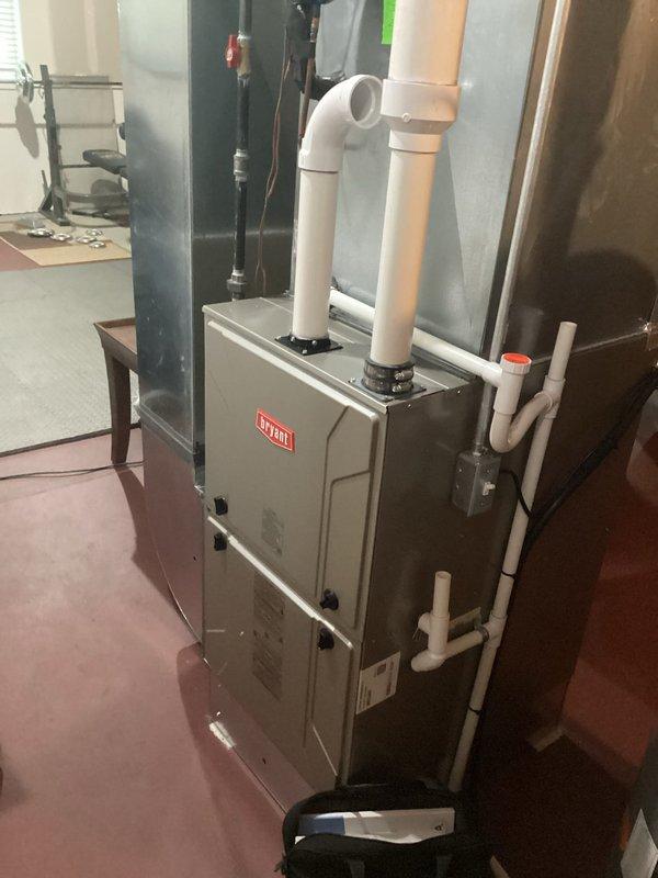 Completed air conditioning replacement estimate for residential HVAC system. Inspected existing Bryant furnace installation and associated ductwork, photographed current equipment configuration including PVC venting, copper refrigerant lines, and condensate drainage components to document baseline conditions for proposed AC system upgrade.