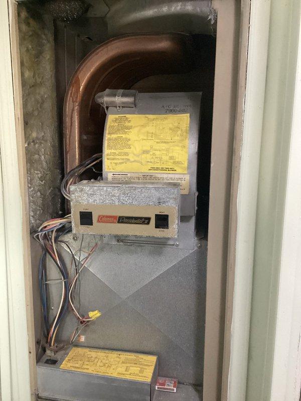 Performed equipment assessment and replacement estimate for 42-year-old Coleman furnace/AC combination system located in utility closet and outdoor condensing unit from 1984. Documented existing equipment condition through photographs showing vertical cabinet-style furnace with worn components, aged copper refrigerant lines, and deteriorating electrical connections. Provided homeowner with comprehensive replacement options for complete HVAC system upgrade due to equipment age and outdoor unit failure.