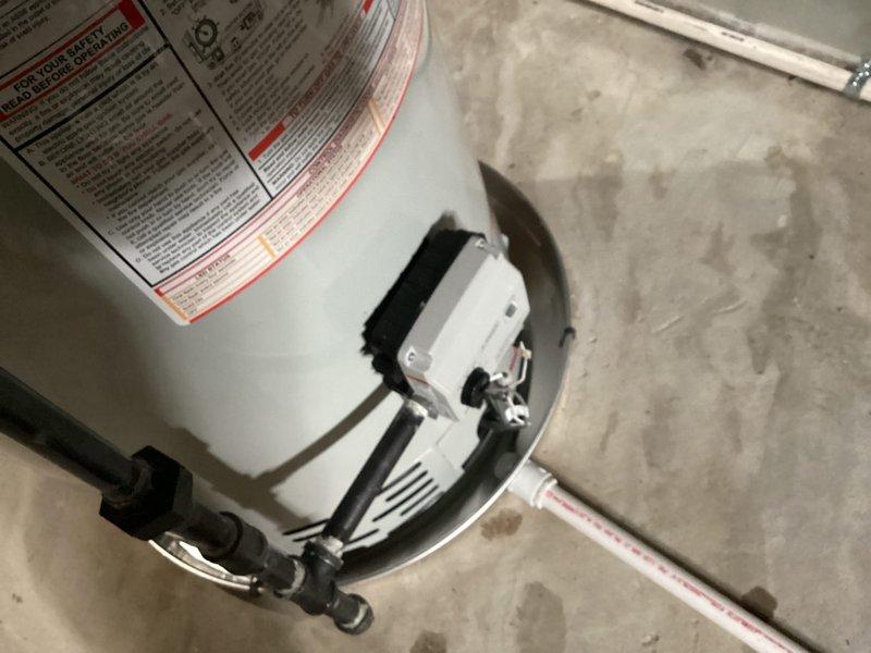 Completed installation of a 50-gallon tanked water heater in basement utility area. Unit was properly positioned on concrete floor with appropriate clearances, gas valve assembly and control module mounted and connected, and all necessary piping and venting completed per manufacturer specifications and local code requirements.
