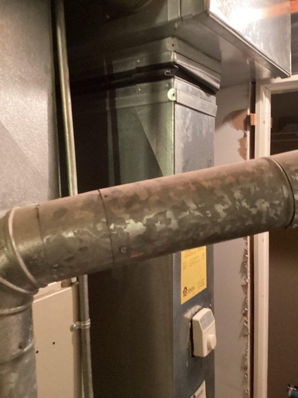 Conducted comprehensive HVAC system evaluation for equipment replacement estimate. Documented existing furnace unit with green metal cabinet showing age-related wear, deteriorated ductwork exhibiting significant surface corrosion and oxidation requiring replacement, and electrical panel configuration for proper system integration. Assessment confirmed need for complete system replacement due to advanced equipment deterioration and compromised duct integrity affecting system efficiency and air quality.
