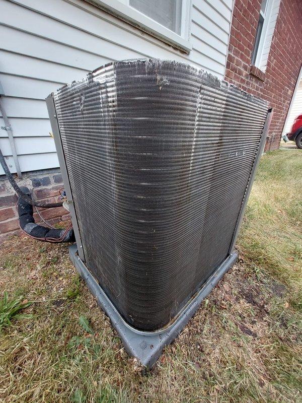 Responded to no cooling complaint on 2-year-old residential AC system with secondary issue of lights dimming when unit operates and inadequate airflow to upper level. Performed diagnostic inspection of outdoor condenser unit, finding heavily soiled condenser coils with significant dirt, dust, and debris accumulation restricting airflow and reducing heat transfer efficiency. Documented condenser condition with photographs showing external buildup on fins and overall unit configuration. Assessed electrical connections, refrigerant lines, and compressor mounting for proper installation and operation. Recommended professional coil cleaning to restore system capacity and efficiency, along with evaluation of electrical service to address voltage drop causing lights to dim during compressor startup, which may indicate undersized circuit or loose connections requiring immediate attention to prevent equipment damage.