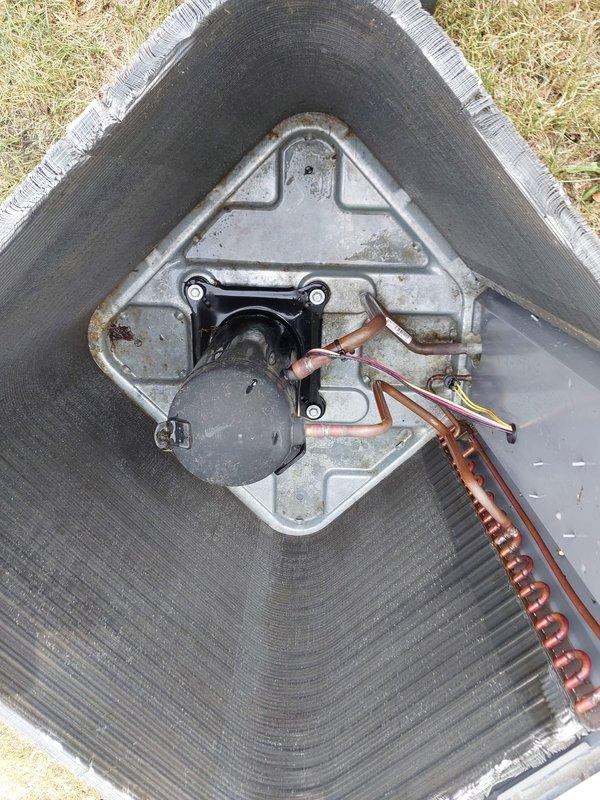 Responded to no cooling complaint on 2-year-old residential AC system with secondary issue of lights dimming when unit operates and inadequate airflow to upper level. Performed diagnostic inspection of outdoor condenser unit, finding heavily soiled condenser coils with significant dirt, dust, and debris accumulation restricting airflow and reducing heat transfer efficiency. Documented condenser condition with photographs showing external buildup on fins and overall unit configuration. Assessed electrical connections, refrigerant lines, and compressor mounting for proper installation and operation. Recommended professional coil cleaning to restore system capacity and efficiency, along with evaluation of electrical service to address voltage drop causing lights to dim during compressor startup, which may indicate undersized circuit or loose connections requiring immediate attention to prevent equipment damage.