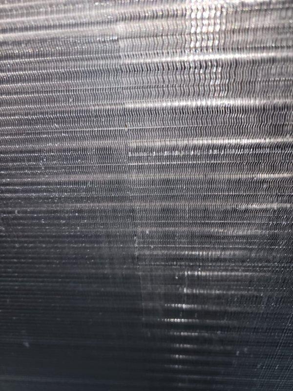 Completed scheduled cooling system tune-up and maintenance on properly functioning HVAC unit. Inspected and photographed condenser coil fins showing partial dirt accumulation on lower section, compressor unit with refrigerant lines and electrical connections, and verified all components operating within normal parameters. System confirmed working properly with no repairs required.
