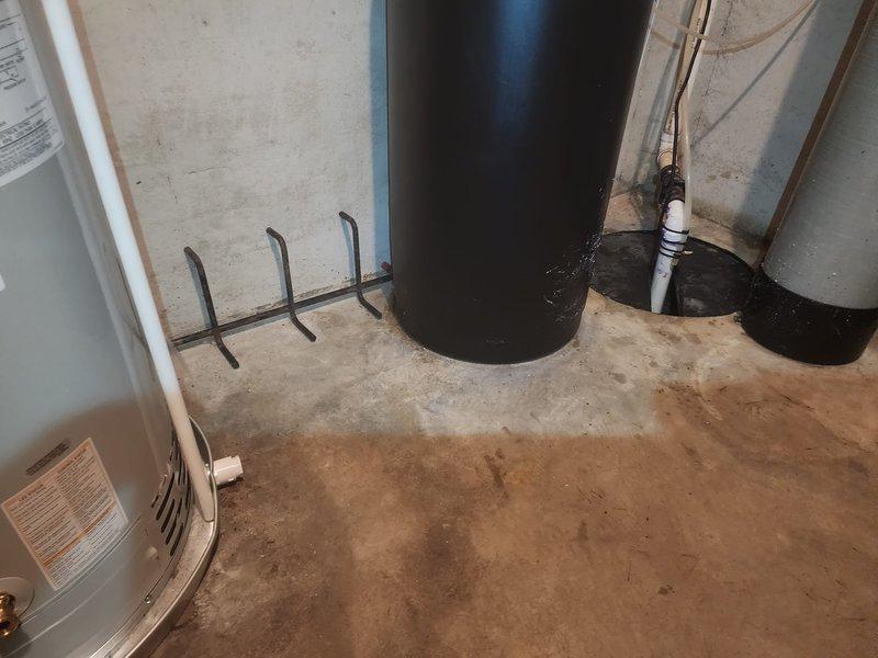 Completed installation of 50-gallon tanked water heater in basement utility area, replacing existing unit. Connected all copper supply lines, installed proper venting through exterior wall with white PVC piping and blue valve assembly, and secured unit per code requirements with appropriate mounting hardware on concrete foundation.