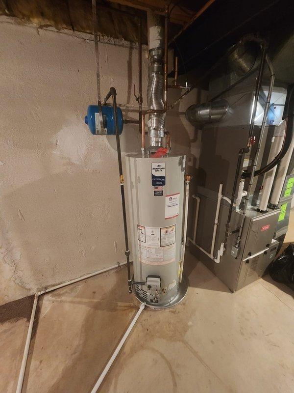 Completed installation of a 40-gallon Bradford White tank-style water heater in basement utility area. Connected copper supply lines with shut-off valves, installed expansion tank, and verified proper venting and drainage systems. All plumbing connections tested and operational upon completion.