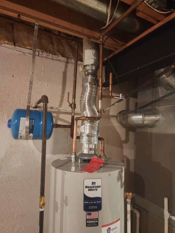 Completed installation of a 40-gallon Bradford White tank-style water heater in basement utility area. Connected copper supply lines with shut-off valves, installed expansion tank, and verified proper venting and drainage systems. All plumbing connections tested and operational upon completion.