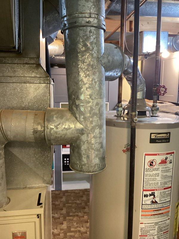 Conducted comprehensive HVAC system evaluation for residential replacement estimate. Assessed aging air handler unit (25-30 years old) located in utility space, documenting existing equipment condition including accumulated dust, weathered surfaces, and outdated control systems. Evaluated associated ductwork infrastructure, noting flexible metallic ducting connections and insulation requirements. Photographed equipment specifications, manufacturer data plates, and surrounding mechanical systems including galvanized ductwork with visible corrosion and moisture staining. Provided complete system replacement recommendations based on equipment age, efficiency standards, and observed deterioration of components.
