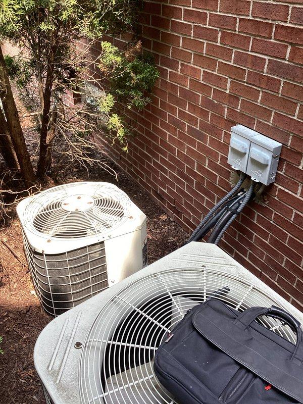Conducted on-site evaluation for replacement of two 37-year-old furnaces located in basement and two 37-year-old air conditioning condensers positioned outside against brick exterior. All existing equipment currently operational with no reported symptoms or safety concerns. Inspected both outdoor condenser units, documented equipment conditions, and assessed installation locations including electrical disconnects, refrigerant line routing, and clearances. Photographed existing HVAC systems to prepare comprehensive replacement proposals including both standard efficiency and high-efficiency equipment options as requested.