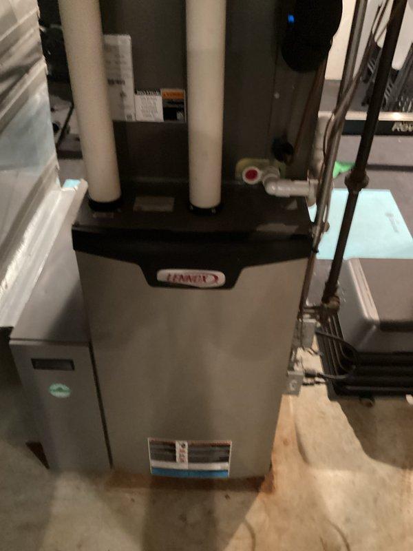 Completed comprehensive equipment replacement estimate for residential HVAC system in basement utility area. Evaluated existing Lennox furnace installation with vertical PVC venting configuration, adjacent air handler cabinet unit, and associated refrigerant lines with visible service valves. Documented current system layout including condensate drainage, electrical connections, exposed ductwork, and equipment positioning on concrete pad for replacement specifications and sizing requirements.