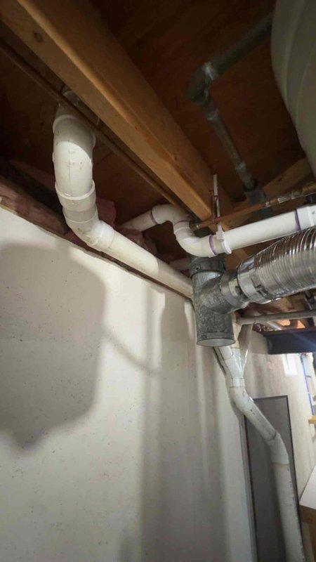 Installed combustion air supply system to mechanical room to meet required 3,300 cubic feet ventilation capacity per code requirements. Routed white PVC intake and exhaust piping through exterior wall with proper termination elbows, connecting to HVAC equipment in basement utility area alongside existing ductwork and plumbing infrastructure. Documentation photos captured for warranty compliance and follow-up verification.