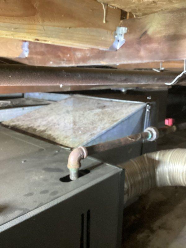 Provided comprehensive estimate for replacement of 15-year-old air conditioning system located in crawl space. Current unit is operational but nearing end of service life, with existing installation showing dust accumulation and age-related wear on metal casing and components. Evaluated existing furnace/air handler configuration positioned among floor joists with copper refrigerant lines, yellow gas line, and metal ductwork with filter assembly, noting tight clearances and accessibility constraints for future replacement work.