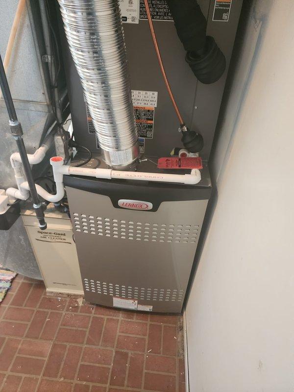 Completed full HVAC system installation including Lennox 80% efficiency furnace and matching air conditioning unit in residential utility space. Installed all necessary refrigerant lines with proper insulation, flexible aluminum ductwork, PVC condensate drainage piping, and copper refrigerant tubing with appropriate connections. Positioned outdoor air conditioning unit in compliance with Milford municipal code requirements, maintaining minimum 5-foot clearance from all building openings. Mounted furnace unit securely on brick paver flooring with proper support brackets and metal framing. Connected all electrical components, safety controls, and manufacturer specification labels affixed per code requirements. System tested and verified operational for both heating and cooling functions.
