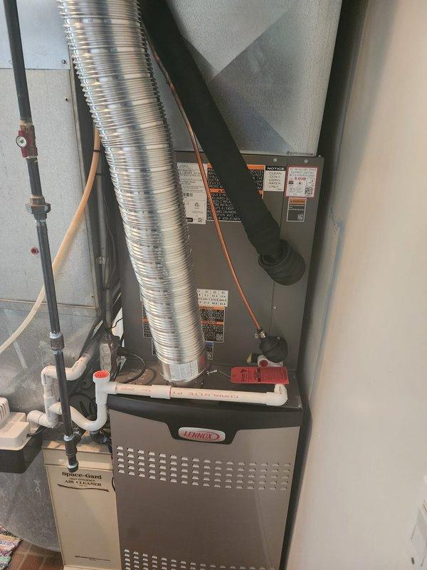 Completed full HVAC system installation including Lennox 80% efficiency furnace and matching air conditioning unit in residential utility space. Installed all necessary refrigerant lines with proper insulation, flexible aluminum ductwork, PVC condensate drainage piping, and copper refrigerant tubing with appropriate connections. Positioned outdoor air conditioning unit in compliance with Milford municipal code requirements, maintaining minimum 5-foot clearance from all building openings. Mounted furnace unit securely on brick paver flooring with proper support brackets and metal framing. Connected all electrical components, safety controls, and manufacturer specification labels affixed per code requirements. System tested and verified operational for both heating and cooling functions.