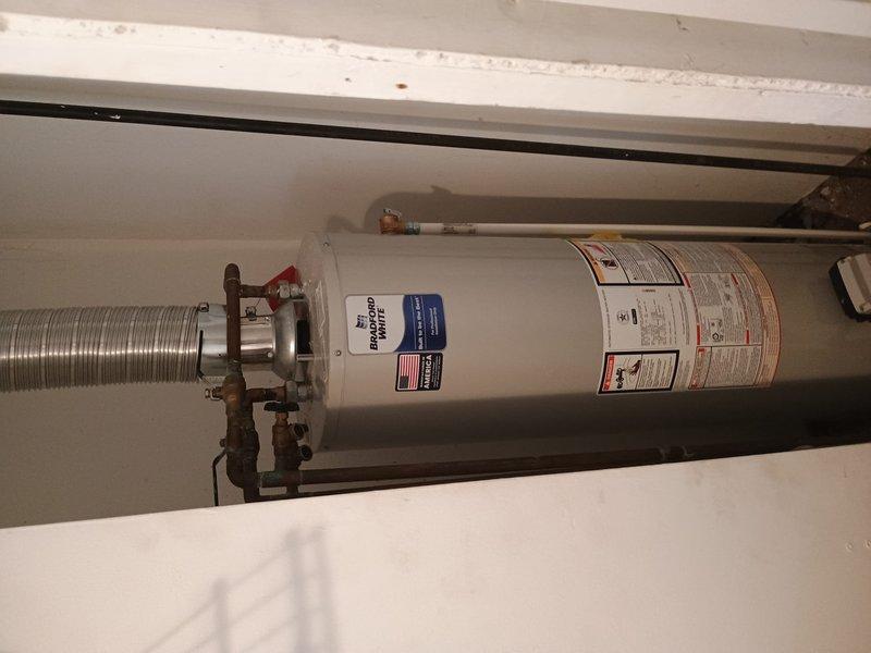 Successfully installed a new 30-gallon tanked water heater in residential utility space, replacing existing aged unit with heavily corroded copper piping. Completed all necessary plumbing connections using copper pipe and brass fittings, including installation of shut-off valves and pressure relief valve. Modified and rerouted furnace venting system to accommodate new water heater placement, installing flexible metallic duct work to ensure proper exhaust ventilation and code compliance. All connections tested and verified for proper operation and leak-free performance.