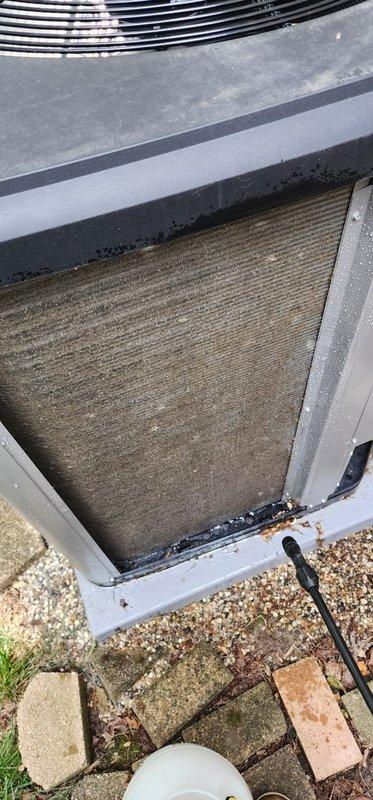 Completed scheduled AC maintenance on outdoor condensing unit. Inspected and documented condition of air filter, which showed significant accumulation of dirt, dust, and debris requiring attention. Filter exhibited heavy soiling with brownish-tan discoloration and visible horizontal striations throughout the mesh material. Photographed unit from multiple angles to document pre-service condition, including top-down views showing cooling coils, metal casing, and filter assembly within frame. Noted debris buildup along filter edges where mesh meets metal frame, indicating restricted airflow conditions that could impact system efficiency and performance if left unaddressed.