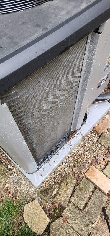 Completed scheduled AC maintenance on outdoor condensing unit. Inspected and documented condition of air filter, which showed significant accumulation of dirt, dust, and debris requiring attention. Filter exhibited heavy soiling with brownish-tan discoloration and visible horizontal striations throughout the mesh material. Photographed unit from multiple angles to document pre-service condition, including top-down views showing cooling coils, metal casing, and filter assembly within frame. Noted debris buildup along filter edges where mesh meets metal frame, indicating restricted airflow conditions that could impact system efficiency and performance if left unaddressed.