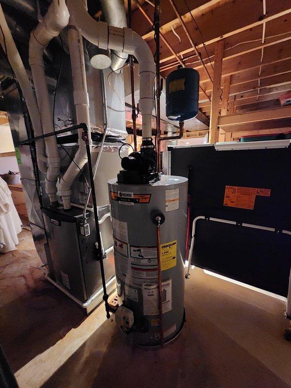 Responded to warranty call for water heater venting inspection. Upon arrival, identified cellular core PVC piping installed as water heater exhaust venting system, which does not meet manufacturer specifications or code requirements for proper combustion gas venting. Documented existing installation showing white PVC vent piping running vertically and horizontally through basement utility area with multiple bends and connections. Photographed complete venting configuration including connections to water heater unit, routing through ceiling joists, and relationship to surrounding HVAC ductwork and plumbing systems. Advised that approved venting materials per installation manual must be used, typically Category III stainless steel or approved polypropylene/CPVC rated for water heater flue gases. Completed required photographic documentation and follow-up form for warranty review and corrective action planning.