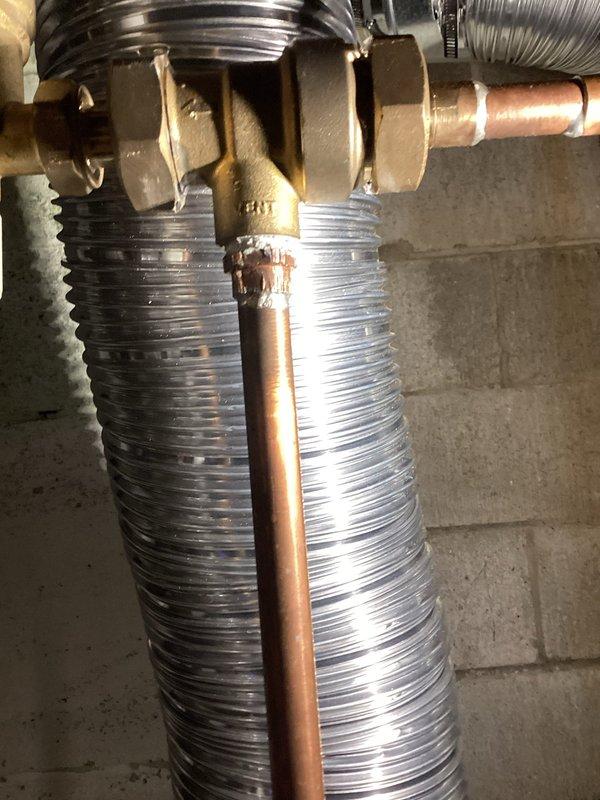 Responded to warranty call for leaking unions on backflow preventer assembly. Upon inspection, identified both threaded union connections on the brass backflow device were actively leaking. Tightened both unions to manufacturer specifications and verified proper seal. Documented existing plumbing configuration including copper supply lines, flexible corrugated connections, and pressure relief valve. System tested and confirmed leak-free operation upon completion.