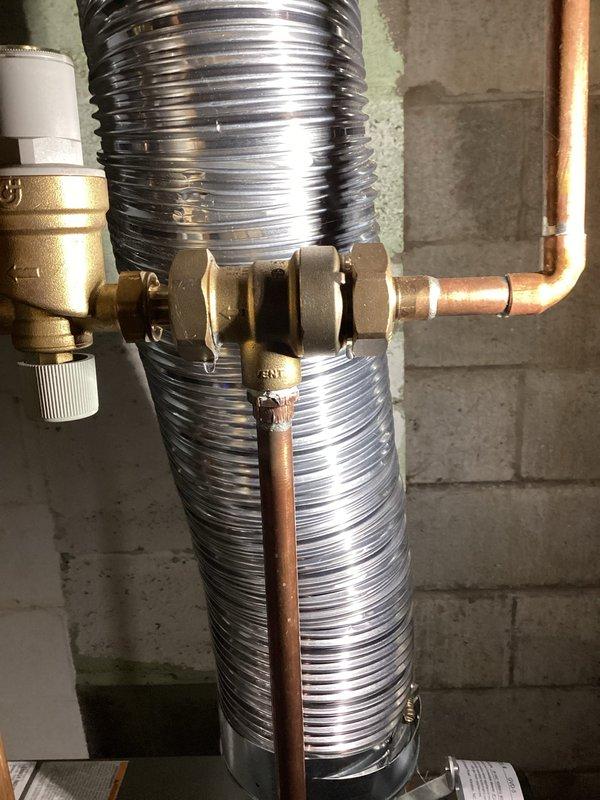 Responded to warranty call for leaking unions on backflow preventer assembly. Upon inspection, identified both threaded union connections on the brass backflow device were actively leaking. Tightened both unions to manufacturer specifications and verified proper seal. Documented existing plumbing configuration including copper supply lines, flexible corrugated connections, and pressure relief valve. System tested and confirmed leak-free operation upon completion.