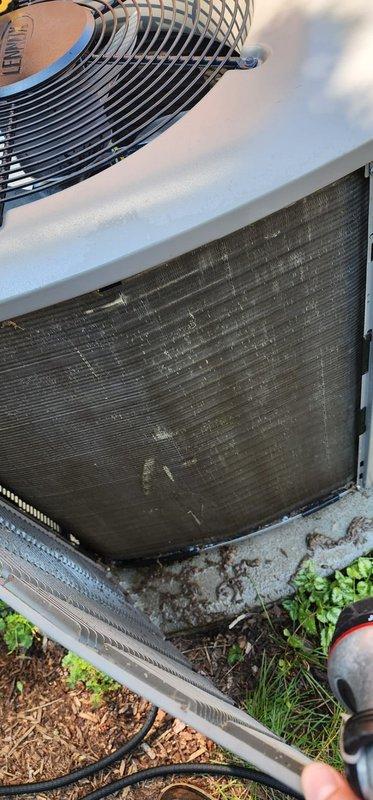 Completed scheduled A/C maintenance on residential split system. Inspected outdoor condenser unit and found heat exchanger coils heavily soiled with dirt, dust, and debris accumulation between fins. Documented significant frost buildup on indoor evaporator coil assembly and refrigerant lines, indicating proper system operation under cooling load. Photographed equipment condition for maintenance records.