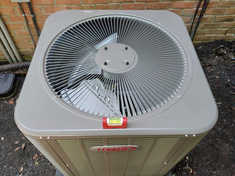 Responded to callback regarding unlevel outdoor condensing unit. Upon arrival, accessed property using provided gate code. Inspected Lennox AC condenser positioned on plastic base pad against brick exterior wall. Unit was slightly unlevel as reported. Verified condenser positioning and stability on pad. Documented equipment condition with photos showing unit placement, surrounding area, and refrigerant line connections. Equipment operational with no immediate safety concerns noted.