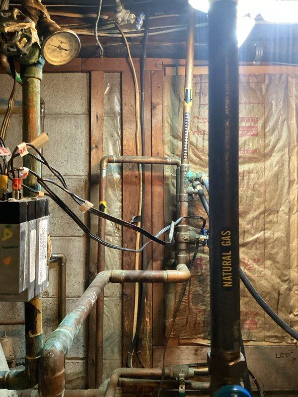 Provided estimate for replacement of 40-year-old boiler system currently operating on natural gas in basement utility area. Assessed existing mechanical infrastructure including aged copper piping showing significant corrosion, natural gas supply lines, and current boiler configuration within unfinished basement space with exposed framing and insulation. Documented equipment condition and surrounding utility connections to prepare comprehensive replacement proposal for aging heating system.