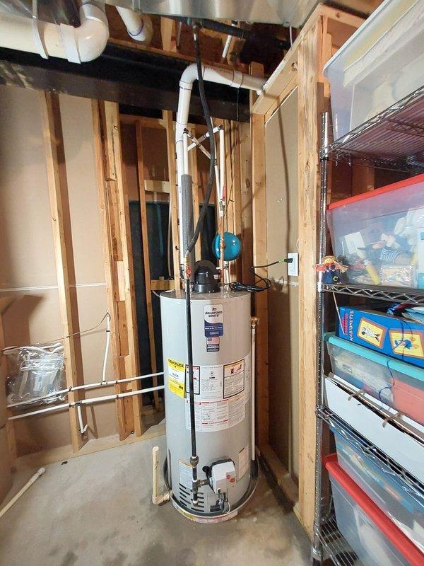 Replaced existing 50-gallon power vent gas water heater with new unit in residential basement utility room. Installation included connecting white PVC venting system to exhaust combustion gases, copper water supply lines with shutoff valves, and gas line connections. Mounted blue thermal expansion tank at top of unit to accommodate system pressure fluctuations and installed pressure relief valve with discharge piping per code requirements. Verified all connections for proper operation, checked for gas leaks, tested temperature and pressure relief valve functionality, and confirmed proper venting and combustion air supply. Unit installed in unfinished basement area with adequate clearance from combustible materials and accessibility for future maintenance.