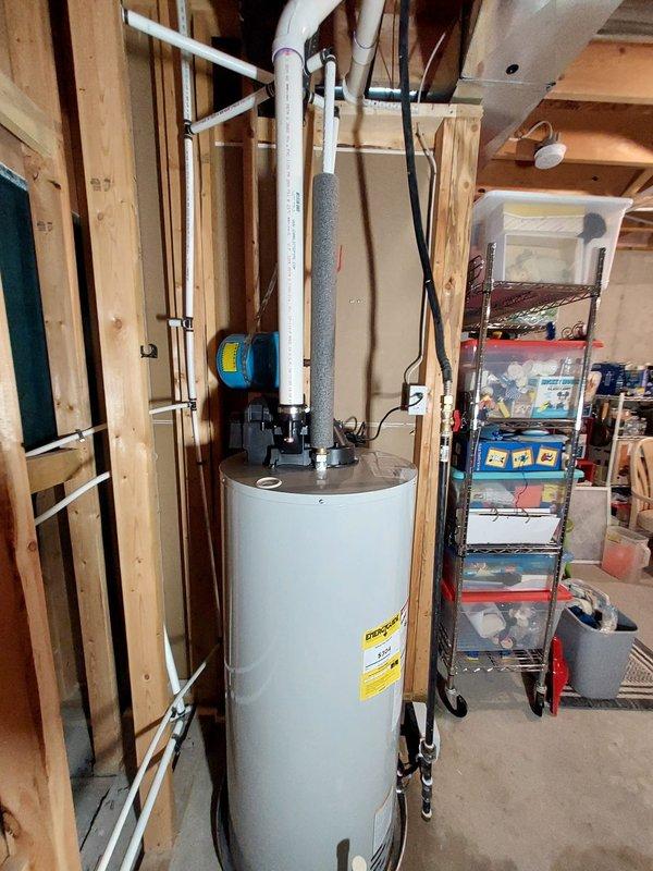 Replaced existing 50-gallon power vent gas water heater with new unit in residential basement utility room. Installation included connecting white PVC venting system to exhaust combustion gases, copper water supply lines with shutoff valves, and gas line connections. Mounted blue thermal expansion tank at top of unit to accommodate system pressure fluctuations and installed pressure relief valve with discharge piping per code requirements. Verified all connections for proper operation, checked for gas leaks, tested temperature and pressure relief valve functionality, and confirmed proper venting and combustion air supply. Unit installed in unfinished basement area with adequate clearance from combustible materials and accessibility for future maintenance.